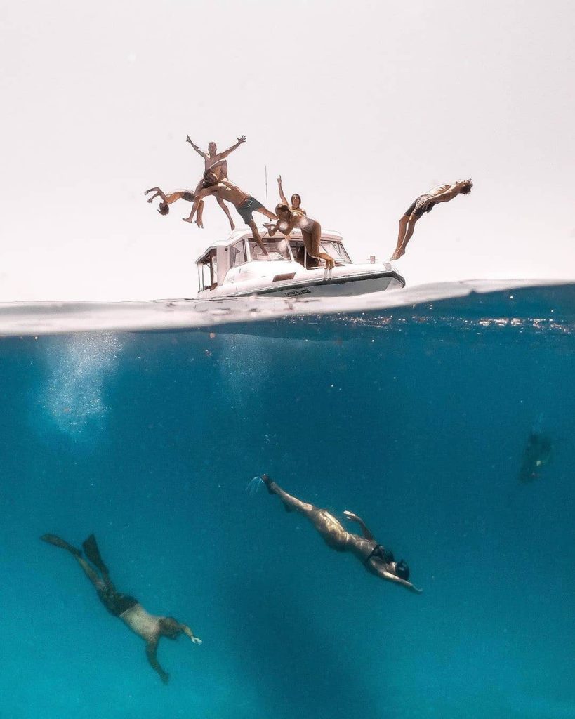 Amigos saltando de un barco a las aguas de Maldivas