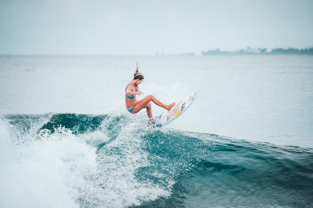 chica surfeando una ola en Maldivas